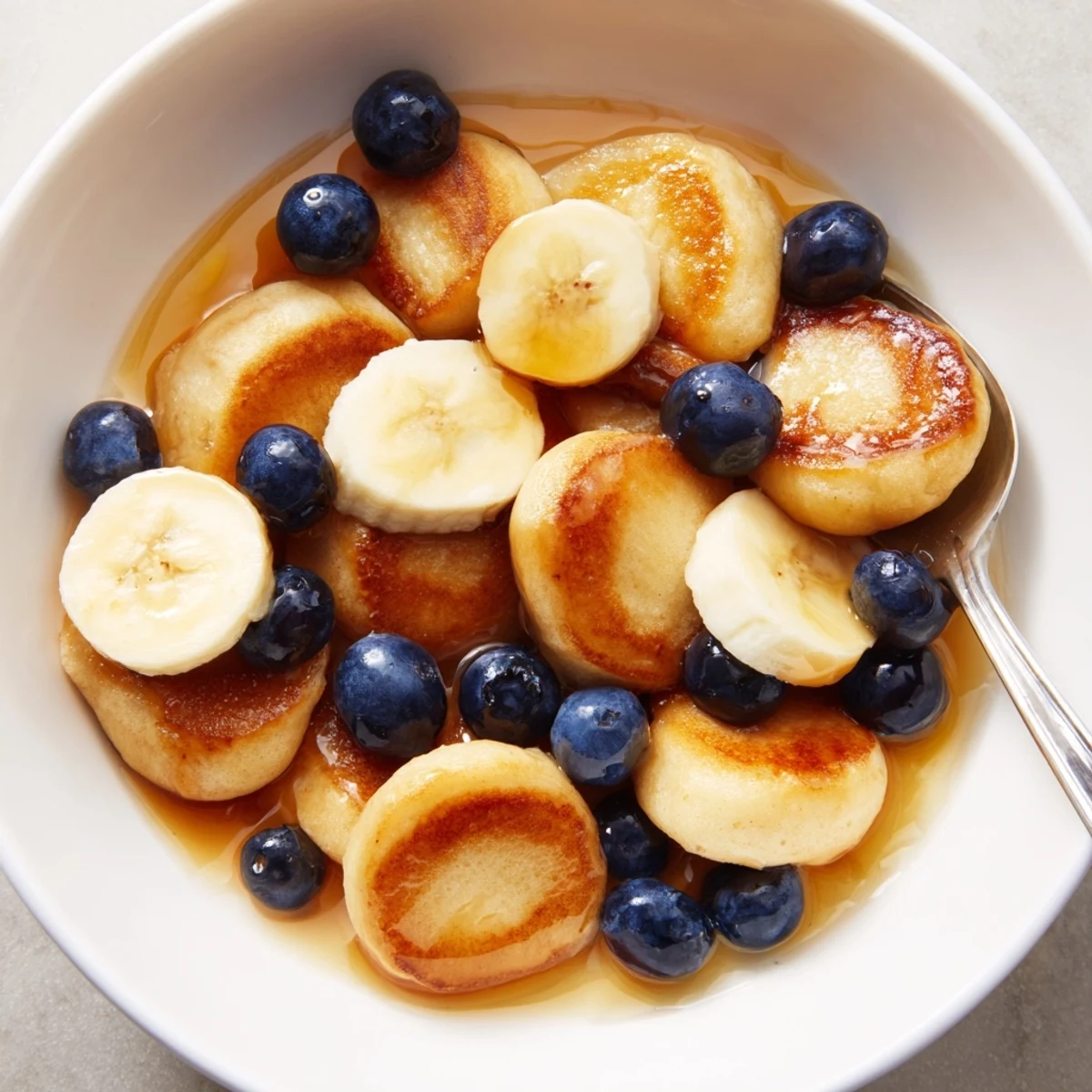 Adorable mini pancake cereal served with milk and fresh berries for breakfast.  