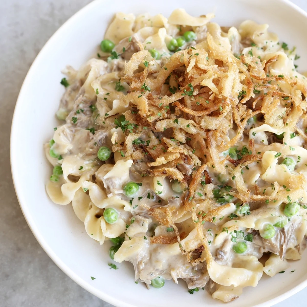 Golden, bubbly Tuna Noodle Casserole with a crispy onion topping, perfect for a cozy weeknight meal.