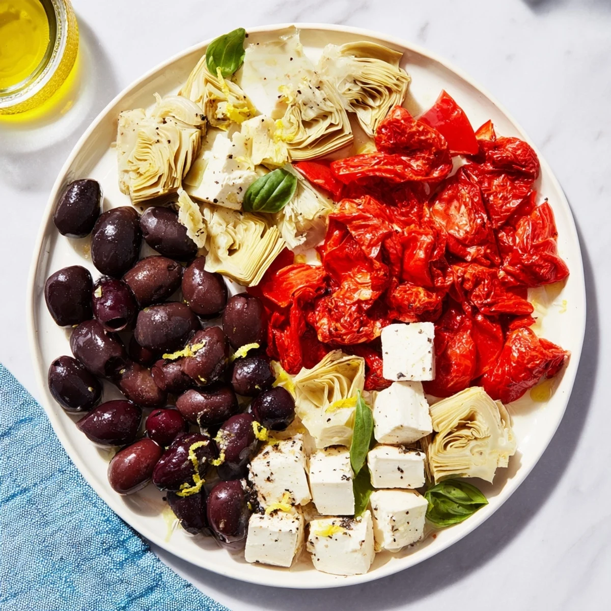 Vibrant Black Olive and Sun-Dried Tomato Platter, ready to serve with feta, olives and fresh herbs.