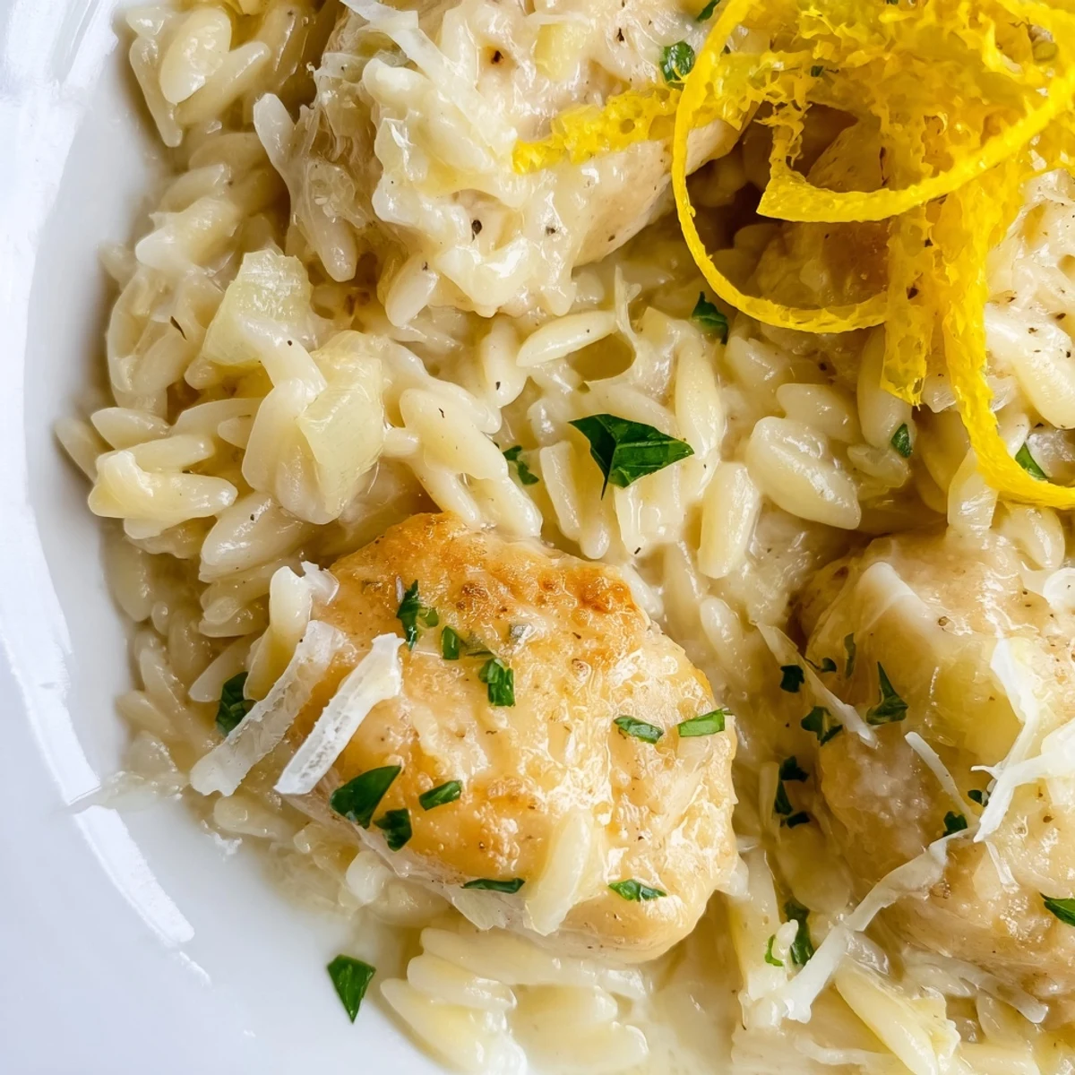 A close-up of Creamy Lemon Chicken Orzo: a delicious plate of creamy pasta with fresh parsley and lemon.