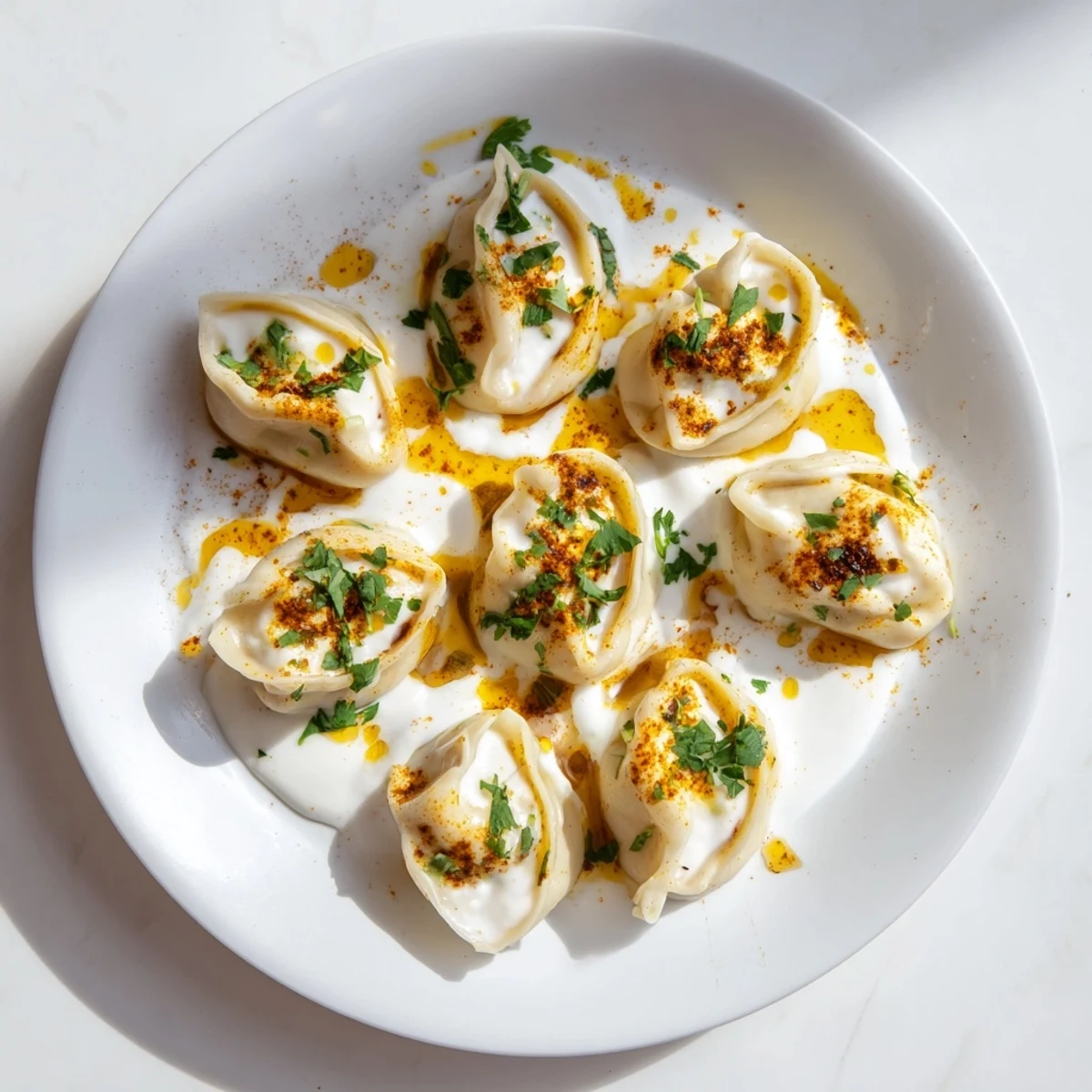 Steaming hot Turkish Cheesy Manti dumplings, topped with creamy yogurt and vibrant red spiced butter.