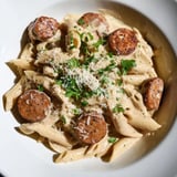 Steaming plate piled high with Cajun Spiced Smoked Sausage Alfredo, ready for a delicious dinner.