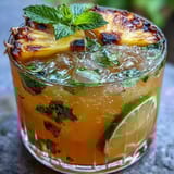 Refreshing pineapple ginger fizz in a tall glass with ice, garnished with lime and mint, perfect for summer gatherings.