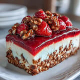 Fresh strawberries peek through jiggly jello atop a creamy strawberry pretzel salad.