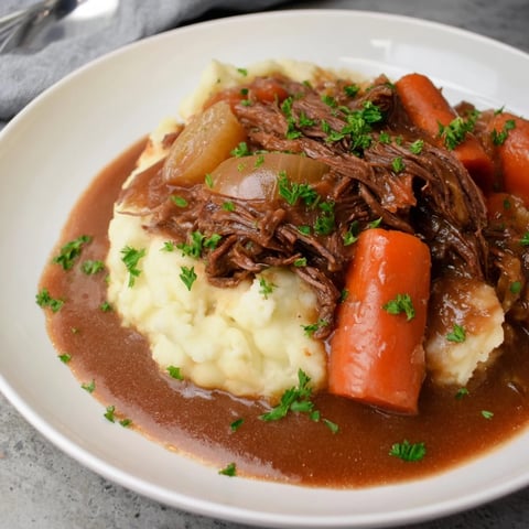 Tender slow cooker pot roast served with creamy mashed potatoes and savory gravy.  