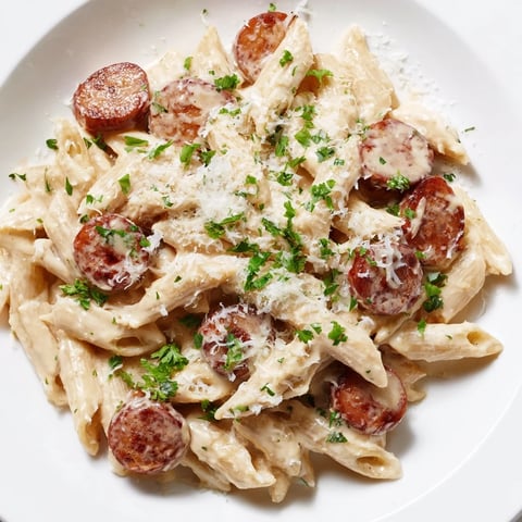 Close-up shot shows a bubbling pot of Cajun Spiced Smoked Sausage Alfredo, creamy and flavorful.