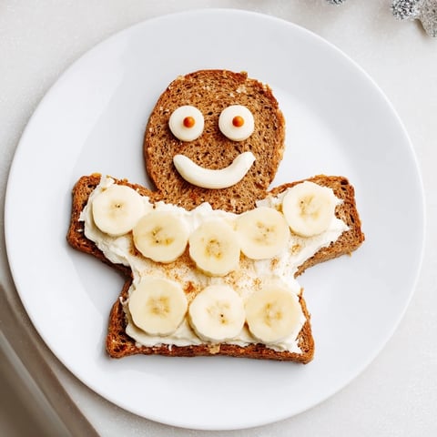 Gingerbread man sandwich cutouts with cream cheese filling, decorated with apple slices and raisins.