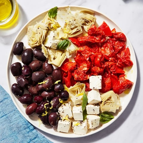 Vibrant Black Olive and Sun-Dried Tomato Platter, ready to serve with feta, olives and fresh herbs.