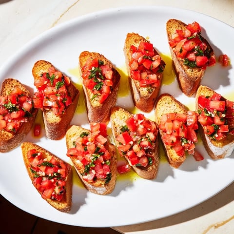 Golden, crispy bruschetta toasts arranged diagonally, topped with fresh tomatoes and basil for a delicious appetizer.