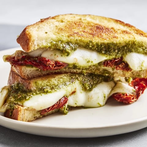 Golden, crispy Pesto Grilled Cheese sandwich, oozing melted mozzarella and vibrant pesto flavors.