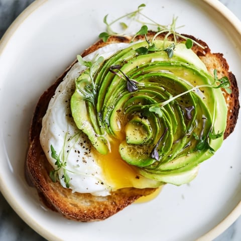 Fluffy cloud toast 2.0 with golden egg whites, creamy avocado roses, and a drizzle of sweet honey.