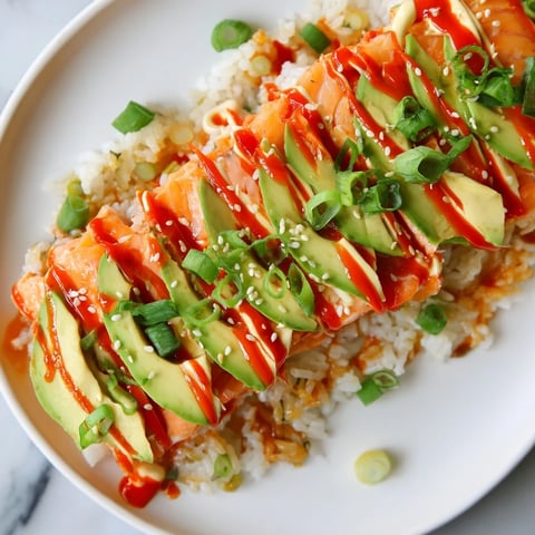 Flaked salmon tops the Emily Mariko Salmon Rice Bowl, served with avocado slices and crisp seaweed.
