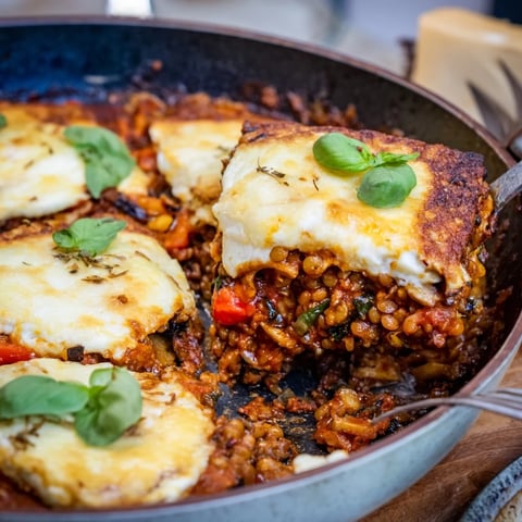 Golden-brown One-Pan Smoky Veggie Lentil Lasagne with melted mozzarella and fresh basil garnish on a rustic wooden table.  