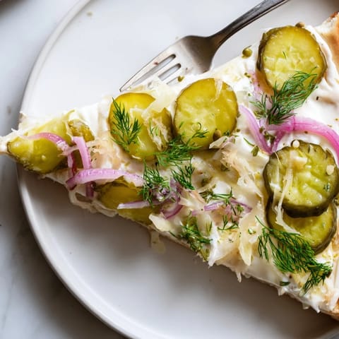 Savor the unique flavor of Pickle Pizza with melted mozzarella and fresh dill garnish.  