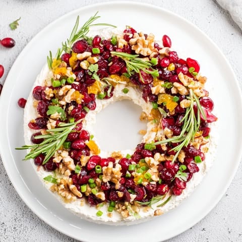 Creamy feta and cranberry dip wreath arranged on a platter, perfect for holiday entertaining with crackers.