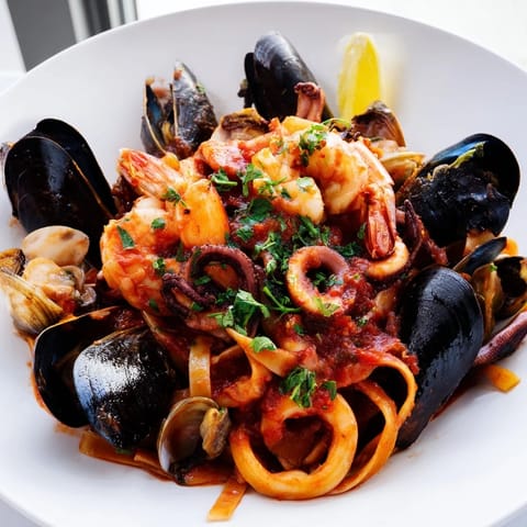 A flavorful bowl of Seafood Marinara Pasta, with a vibrant red sauce, topped with fresh parsley and lemon.