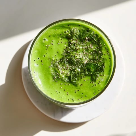 Two glasses of the Green Detox Smoothie, garnished with a slice of apple and a lemon wedge, ready for breakfast.  