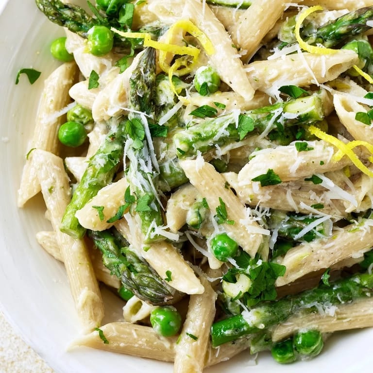 Garlic Parmesan Spring Vegetable Pasta is served warm, garnished with fresh basil and extra Parmesan, perfect for a spring dinner.