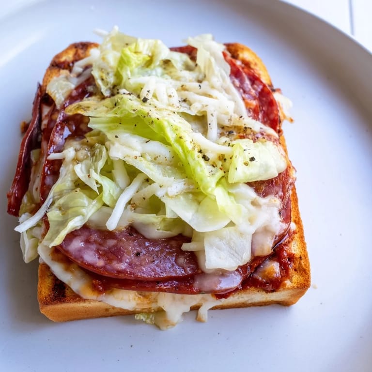 A toasted Italian Sub Grilled Cheese sandwich on a wooden board, garnished with a creamy, tangy shredded lettuce topping.