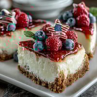 Fourth of July No-Bake Cheesecake Flag Cake with fresh berries arranged in patriotic red, white, and blue stripes on a creamy graham cracker base.