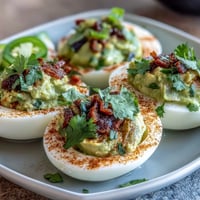 Creamy guacamole stuffed deviled eggs with fresh avocado, lime, and cilantro, perfect for parties and appetizers.